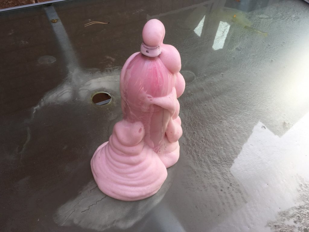 A pink candle on top of a table.