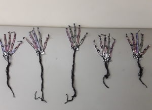 A wall with five skeletons of hands and stems.