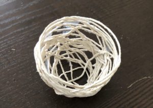 A white bowl with some yarn on top of it