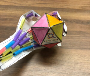 A colorful paper toy with markers on top of it.