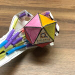 A colorful paper toy with markers on top of it.