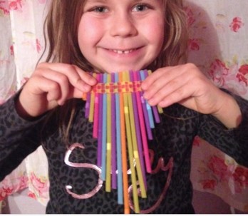 A girl holding up some colorful drinking straws