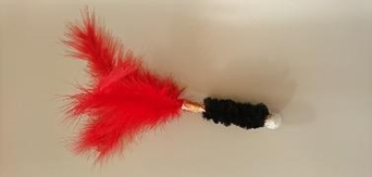 A red and black feather duster on top of a white wall.
