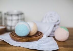 A wooden bowl with three bath bombs on it.