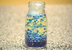 A glass bottle with blue and yellow bubbles inside of it.