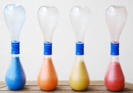 Hourglass Four different colored vases are lined up on a table.