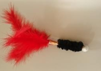 A red and black feather duster on top of a white wall.