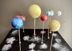 A table topped with lots of cake pops shaped like planets.